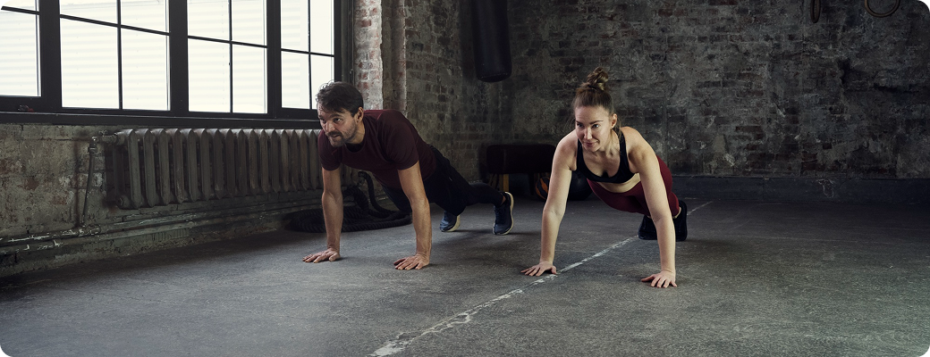 Two people doing plank exercises in industrial setting